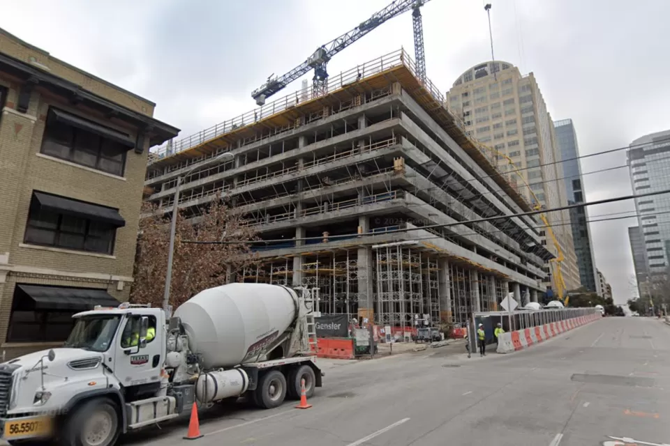 Construction on a high-rise, with cement trucks and tall cranes, is visible on an Austin Street.